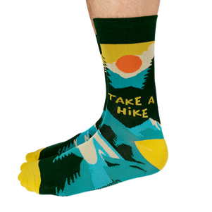 Pair of green, teal, and yellow men's crew socks with a mountain and sun design, featuring the phrase 'Take A Hike' on the side.